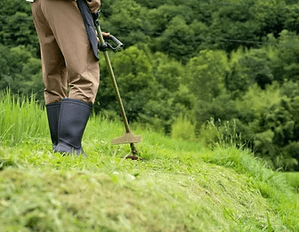 刈払機で斜面の草を刈る作業の様子